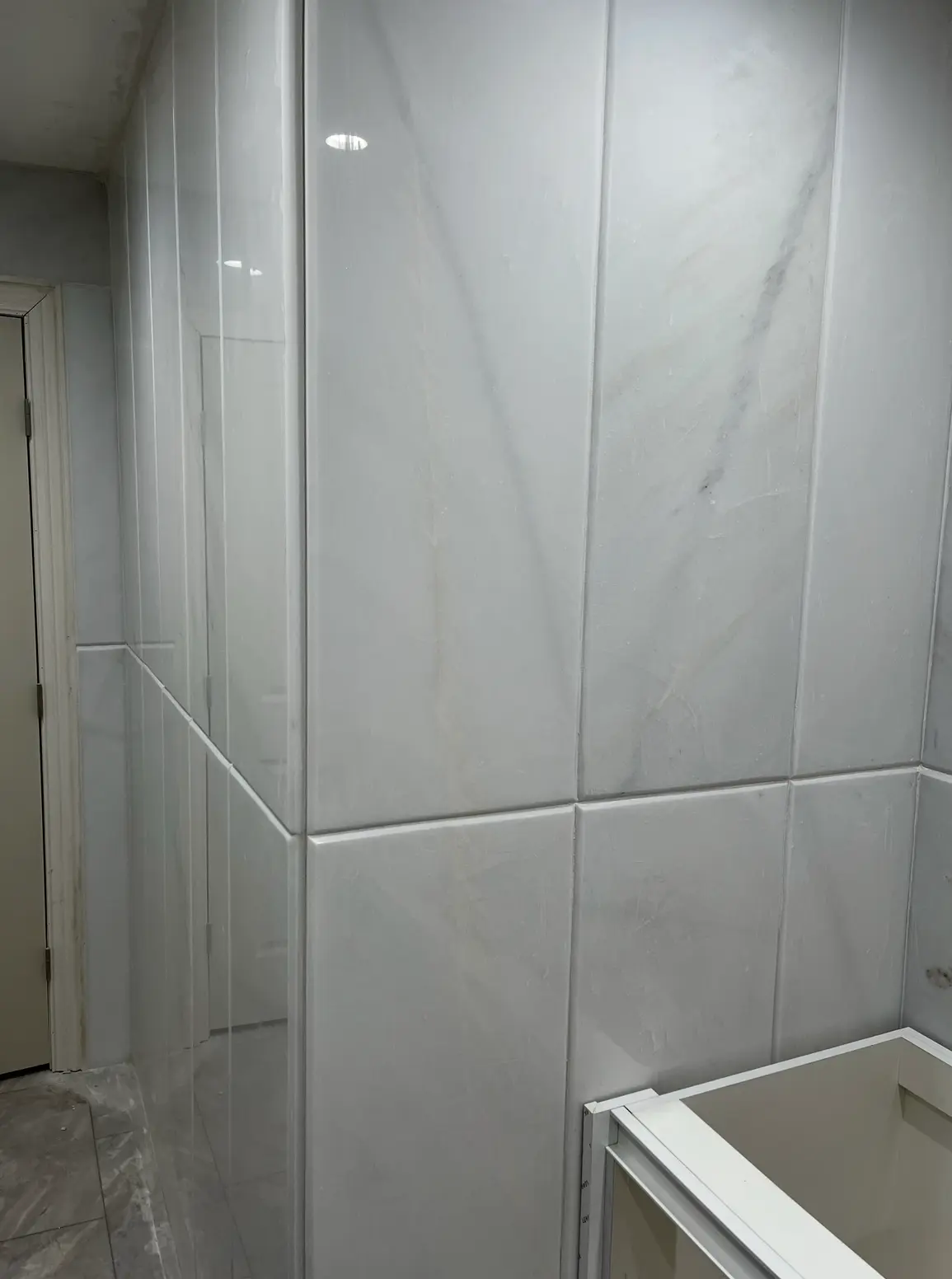 Tall polished white marble wall panels in a bathroom
