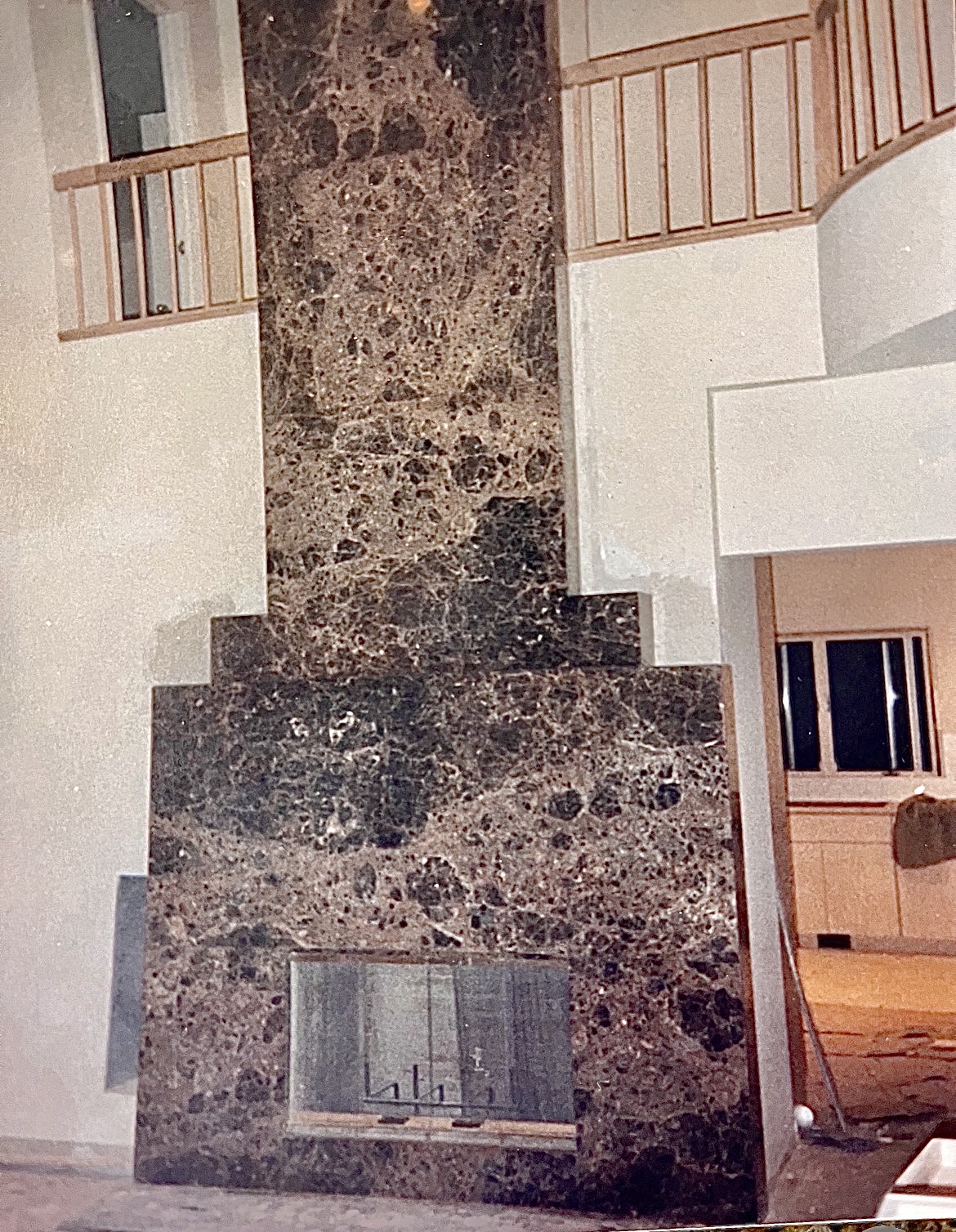 Floor-to-ceiling brown marble fireplace surround in a double-height room