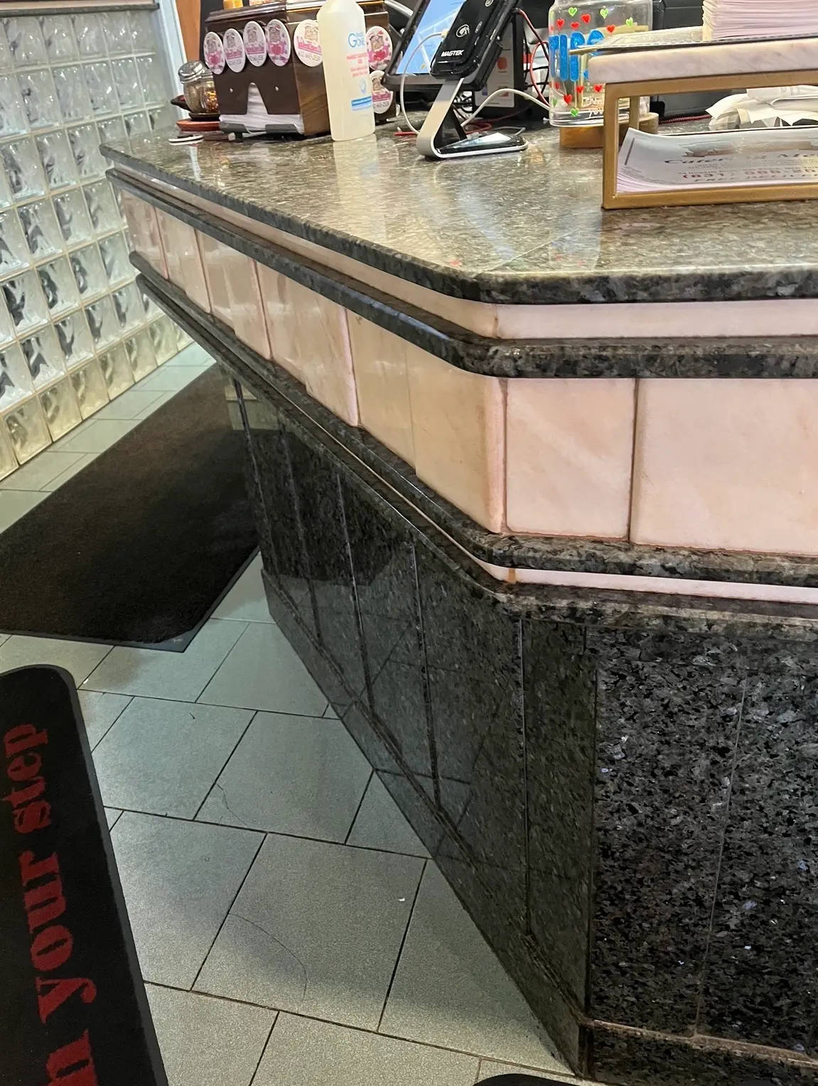 Commercial reception desk clad in dark granite with pink marble banding