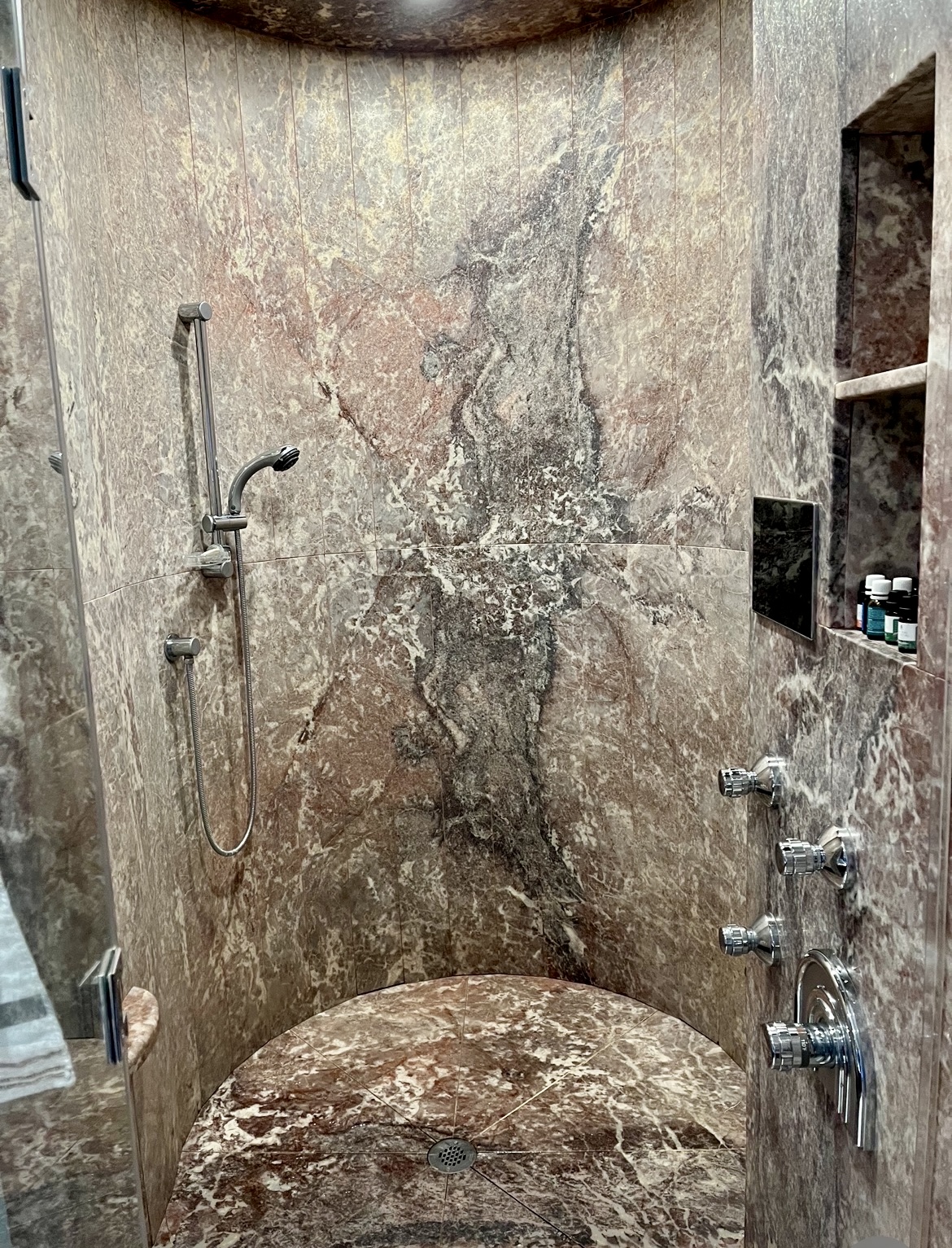 Steam shower clad in veined book-matched marble with curved seat