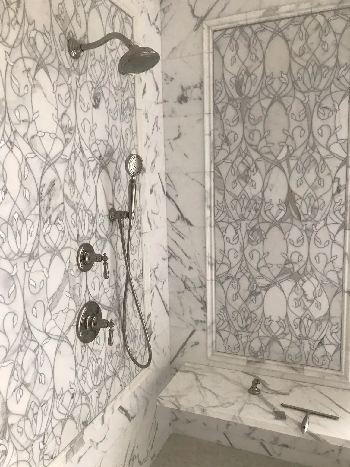 Marble shower wall with rainfall head, hand shower, and decorative marble panel
