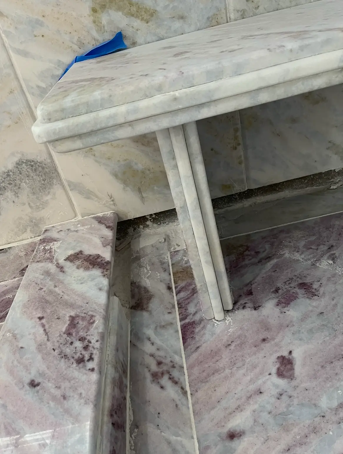 Close-up of a marble shower bench with rounded laminated edge profile