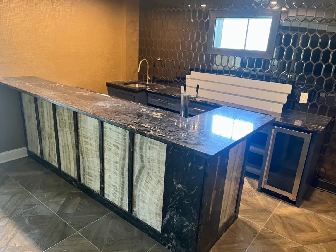 L-shaped wet bar with backlit onyx panels and black granite waterfall end