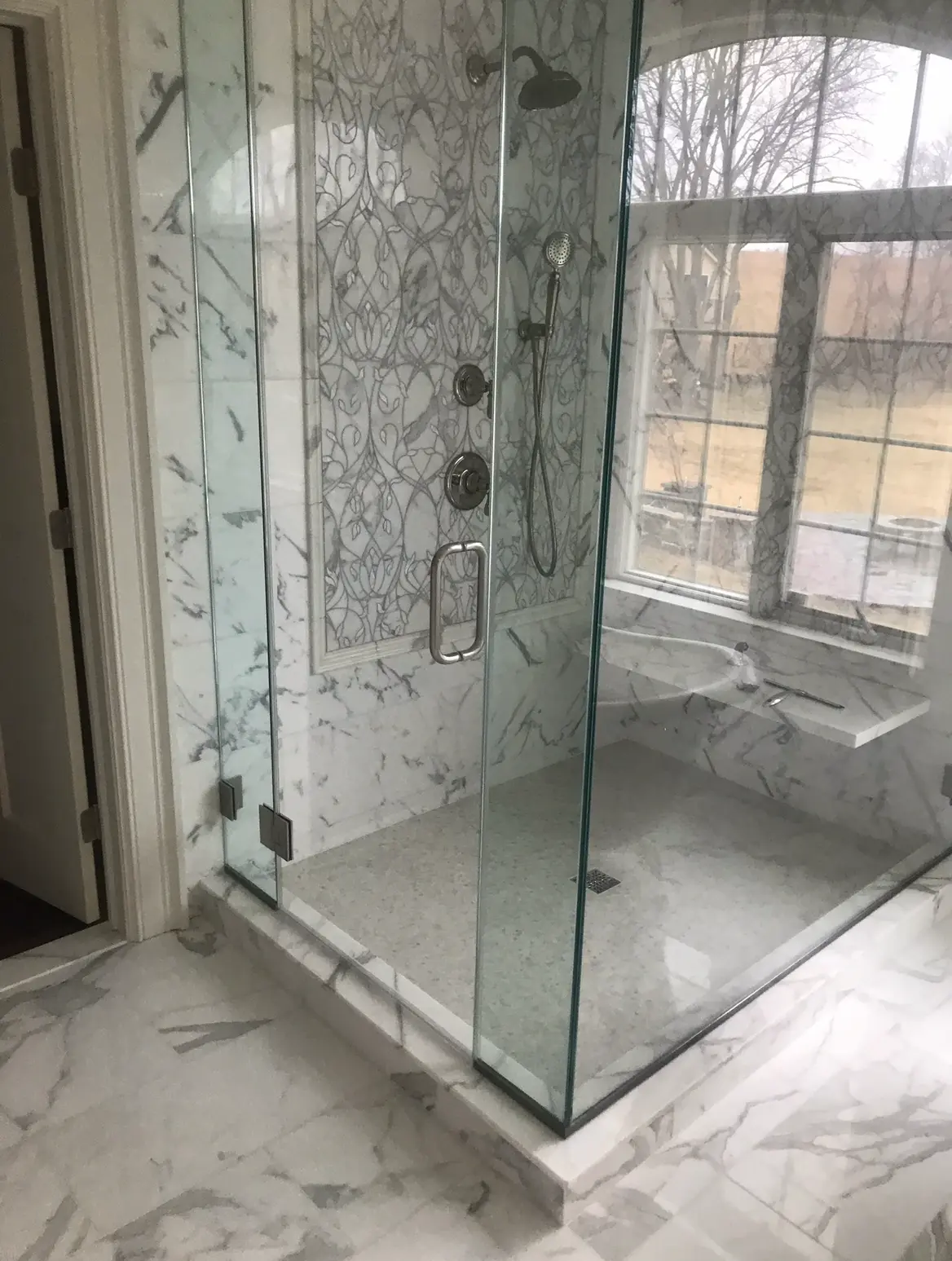 Walk-in marble shower with frameless glass door and window