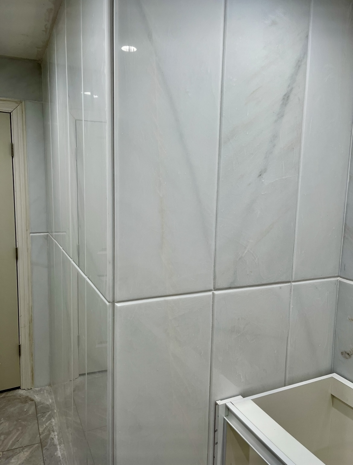 Bathroom walls covered in polished white marble with raised panel detail