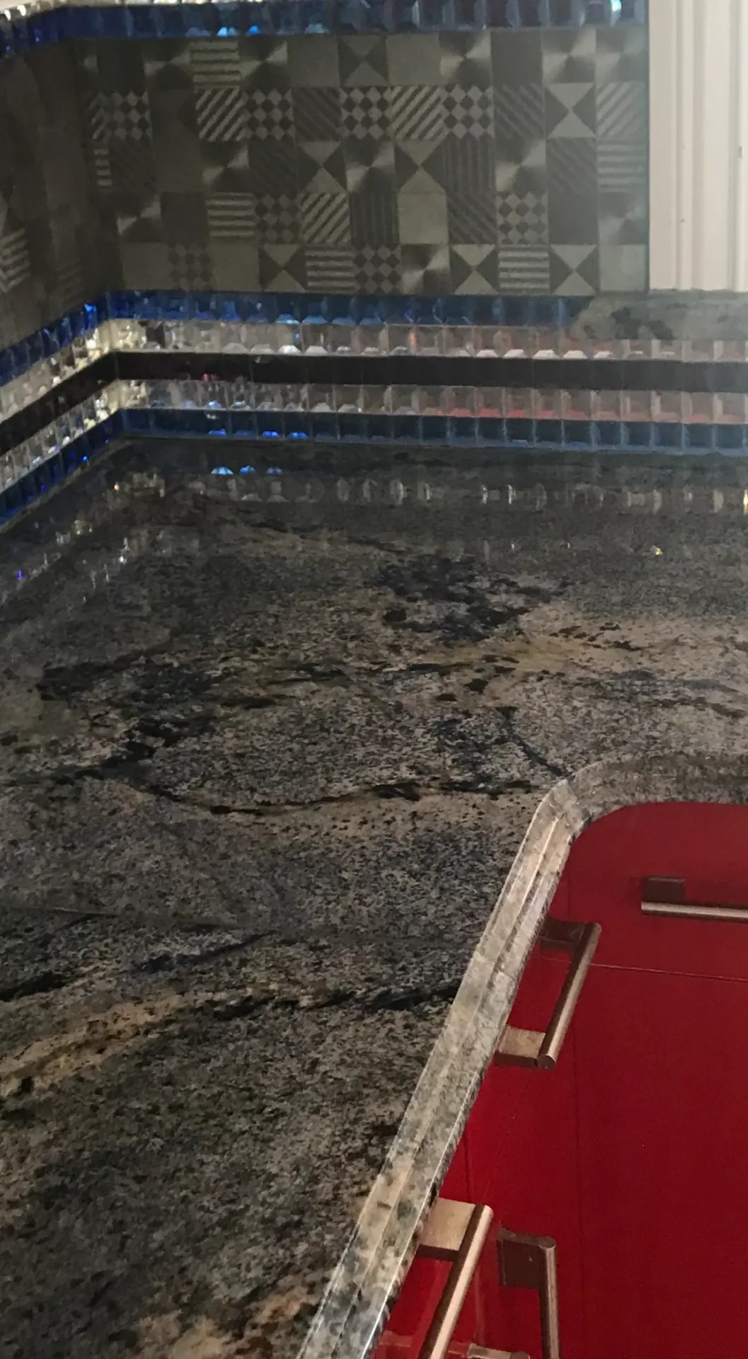Dark polished granite bar countertop with glass tile backsplash