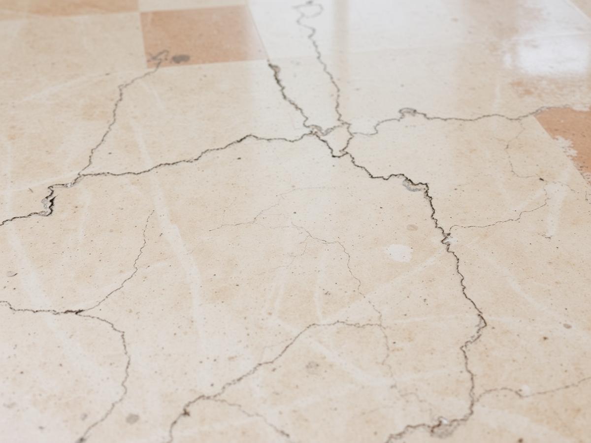Worn marble floor with cracks and staining before restoration